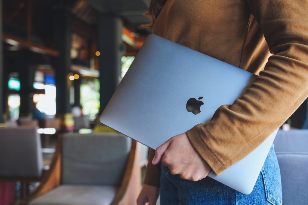 En ung kvinde der holder en Apple macbook under sin arm